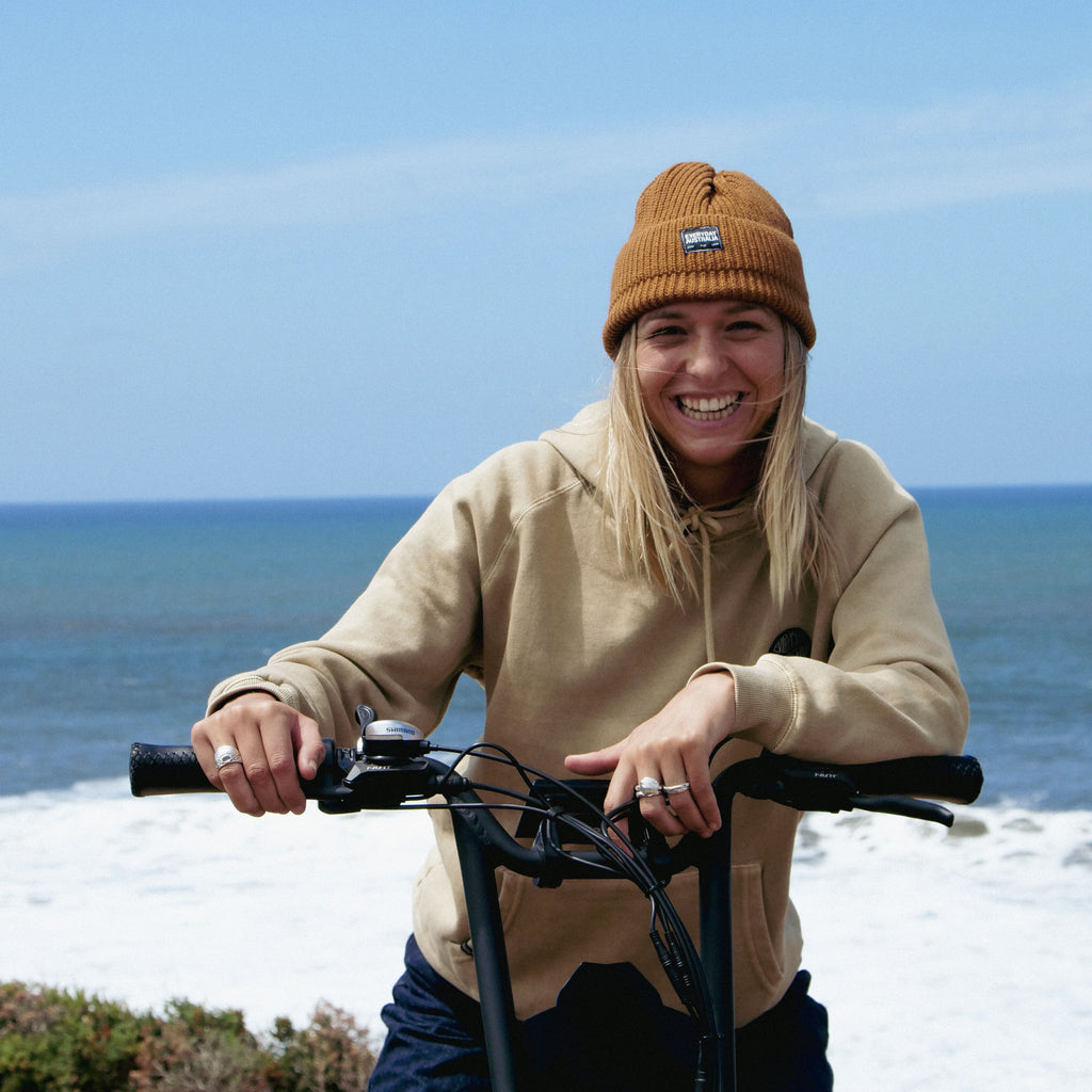 Shop Womens Apparel - girl on bike in EA beanie and hoodie